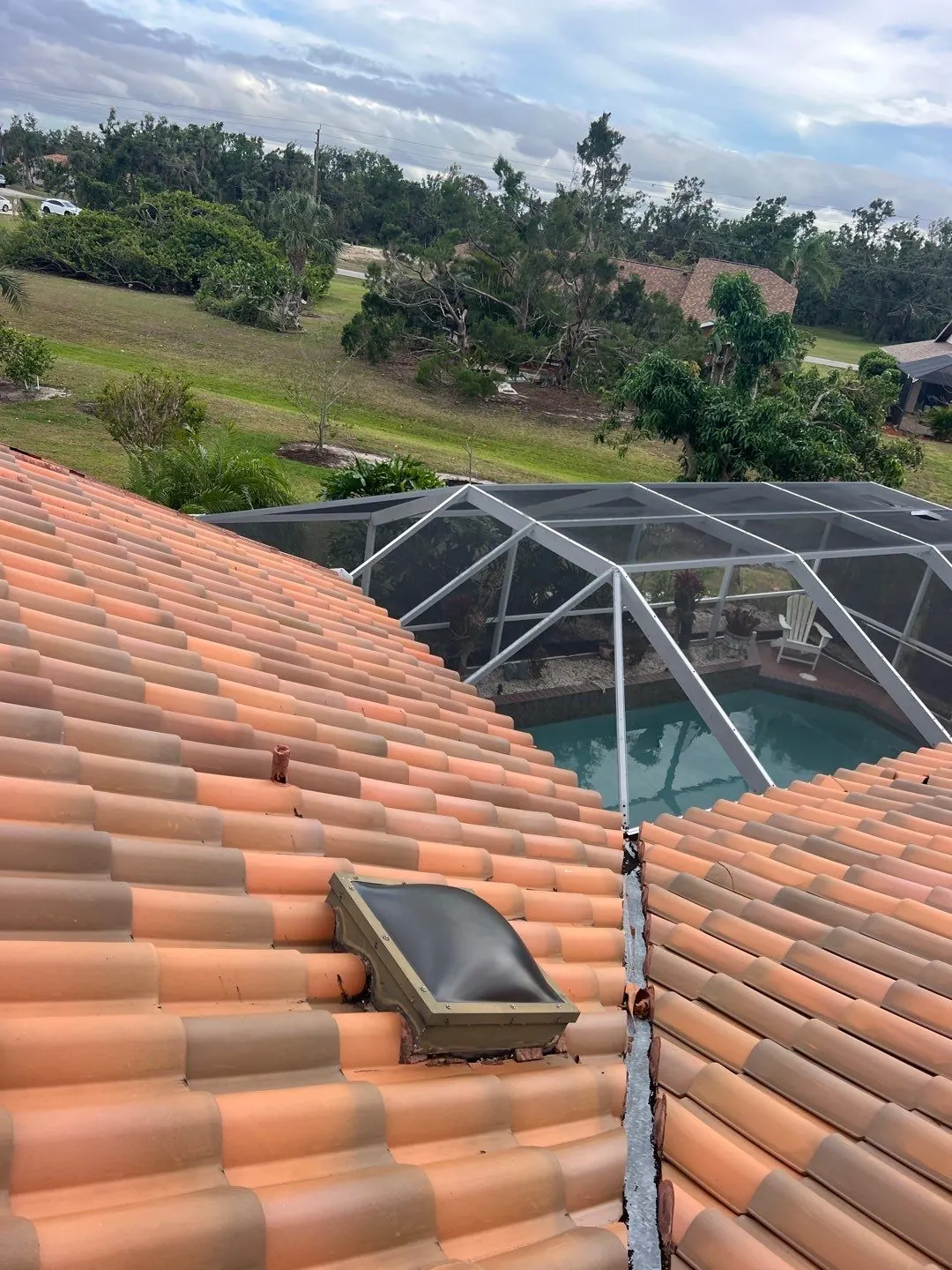 An older barrel tile roof beside a pool cage in Southwest Florida