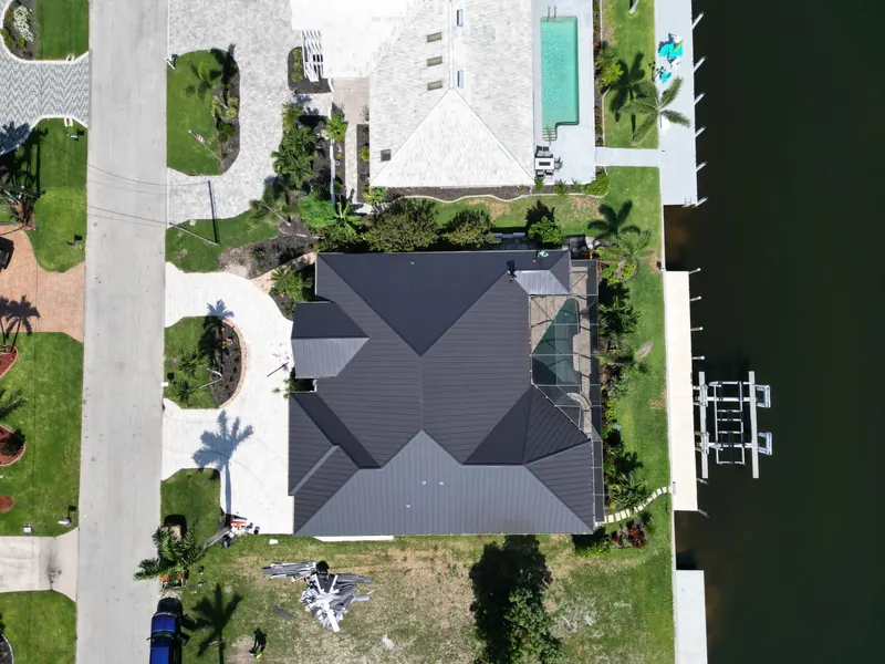 Top-down view of a charcoal metal roof on a canal home with a boat dock