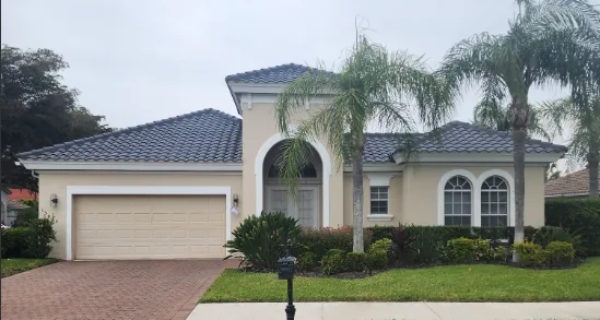 A cream stucco home with a concrete tile roof